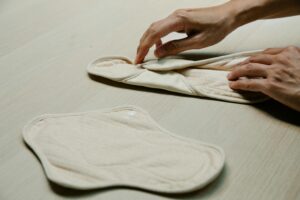 Hands folding reusable menstrual pads, emphasizing sustainability and personal care.